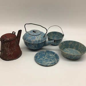 May include: A collection of five metal kitchen items including a weathered red teapot with a handle and four blue and white marbled enamelware pieces consisting of a teapot with a wire handle, a small bucket, a shallow bowl, and a flat circular plate.