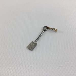 May include: A small, silver toy shovel with a brown string attached to the handle.