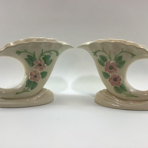 May include: A pair of vintage ceramic cornucopia vases with a floral design. The vases are cream colored with pink and green flowers.