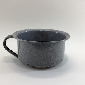 May include: A gray enamelware cup with a handle. The cup has a speckled finish and a small hole in the bottom.