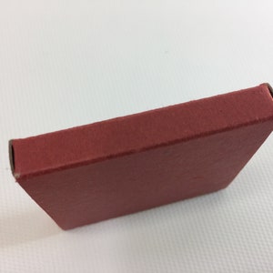 K&ouml;nnte beinhalten: Eine kleine, rote Schachtel aus Pappe mit abgerundeten Ecken.