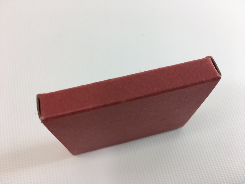 K&ouml;nnte beinhalten: Eine kleine, rote Schachtel aus Pappe mit abgerundeten Ecken.