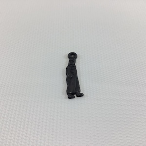 May include: A black metal charm shaped like a person wearing a hat and overalls.