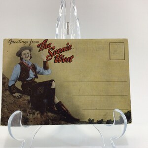 Könnte beinhalten: Vintage-Postkarte mit einer Frau in einem Cowboyhut und einem Outfit, die winkt. Der Text auf der Postkarte lautet "Greetings from The Scenic West".