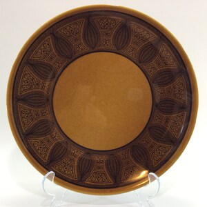 May include: A brown ceramic dinner plate with a dark brown geometric pattern around the rim.