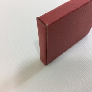K&ouml;nnte beinhalten: Eine kleine, quadratische rote Box mit einem wei&szlig;en Rand.