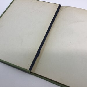 May include: A closed book with a green cover and a blue ribbon bookmark. The book is open to a blank page.