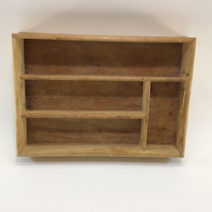 May include: A rectangular wooden organizer with multiple compartments and shelves. The natural wood grain is visible, and the organizer is designed for storage and organization. The design includes a combination of open shelves and vertical dividers.