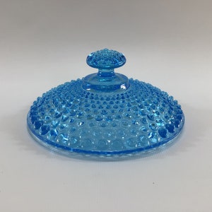 May include: A light blue glass lid with a textured surface and a knob on top. The lid is designed for a bowl or dish.