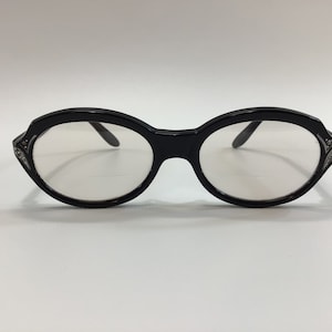 May include: Black oval-shaped eyeglasses with rhinestones on the temples.