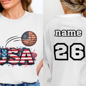White t-shirt with "USA" soccer ball graphic on front, "name 26" on back.