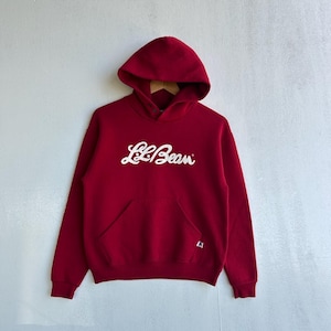 May include: A red hooded sweatshirt with the white text "L.L.Bean" across the chest. The sweatshirt has a kangaroo pocket and a drawstring hood. The brand name is in a cursive font.