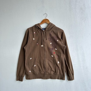 Könnte beinhalten: Brauner Kapuzenpullover mit Reißverschluss, Kapuze und Vordertaschen. Der Hoodie zeigt eine detaillierte Illustration eines Koi-Fisches und Kirschblüten. Das Design ist in Braun-, Rot- und Weißtönen gehalten.