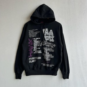 Peut inclure: Sweat-shirt &agrave; capuche noir avec le mot "HAWK" en lettres blanches. Le sweat-shirt pr&eacute;sente divers graphiques textuels en blanc et violet, dont "FRONTSIDE BLUNT". Le sweat &agrave; capuche est fait d'une mati&egrave;re douce.