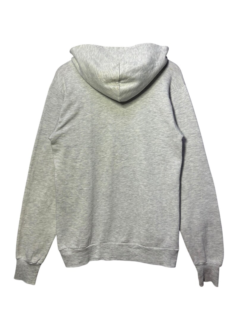 K&ouml;nnte beinhalten: Ein melierter grauer Kapuzenpullover mit Kordelzugkapuze und langen &Auml;rmeln. Das Sweatshirt hat gerippte B&uuml;ndchen und Saum. Die R&uuml;ckansicht des Kapuzenpullovers wird vor wei&szlig;em Hintergrund gezeigt.