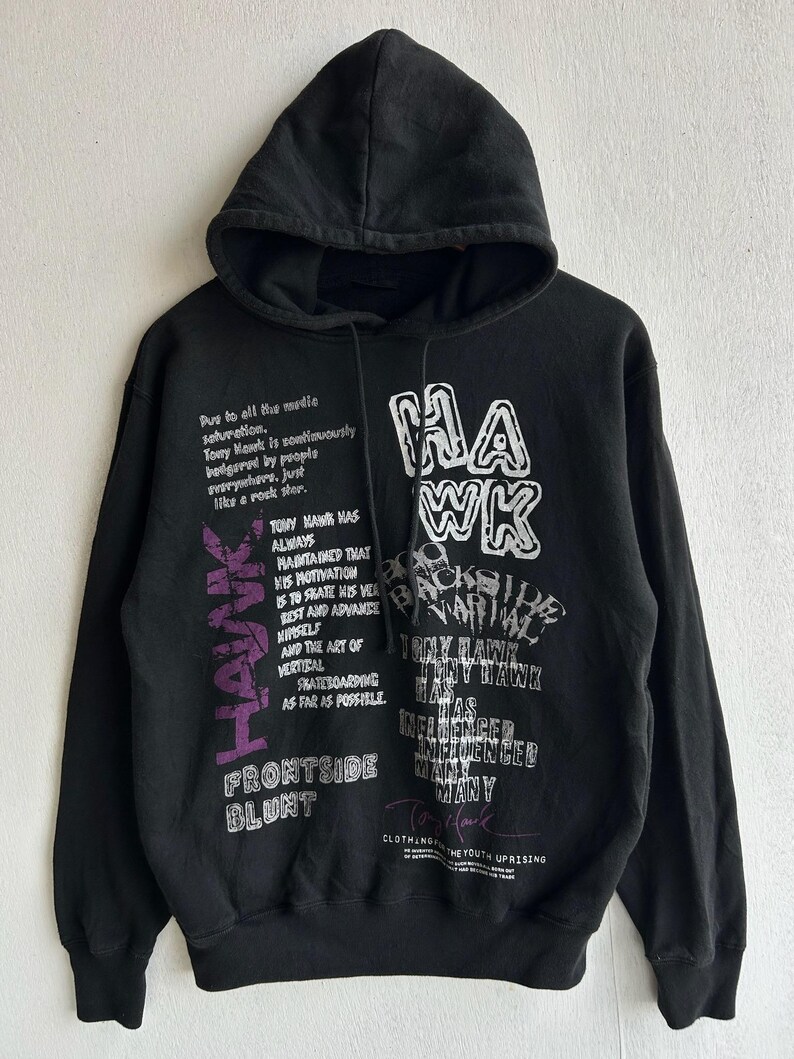 Peut inclure: Sweat &agrave; capuche noir avec cordon de serrage et manches longues. Le devant affiche le mot "HAWK" en blanc et violet, ainsi que du texte sur Tony Hawk et le skateboard. Le sweat &agrave; capuche est en mati&egrave;re douce.
