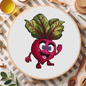 Peut inclure: Un cercle de broderie au point de croix représentant un personnage de betterave de dessin animé avec un visage souriant, des bras et des jambes. La betterave est rouge avec des feuilles vertes et rouges. Le fond est en tissu blanc.