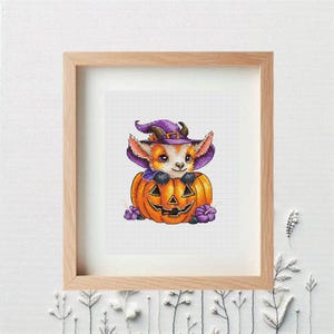 May include: A framed print featuring a whimsical illustration of a goat-like creature wearing a purple witch hat, peeking out of an orange jack-o'-lantern. The artwork includes purple flowers and is set against a white background.
