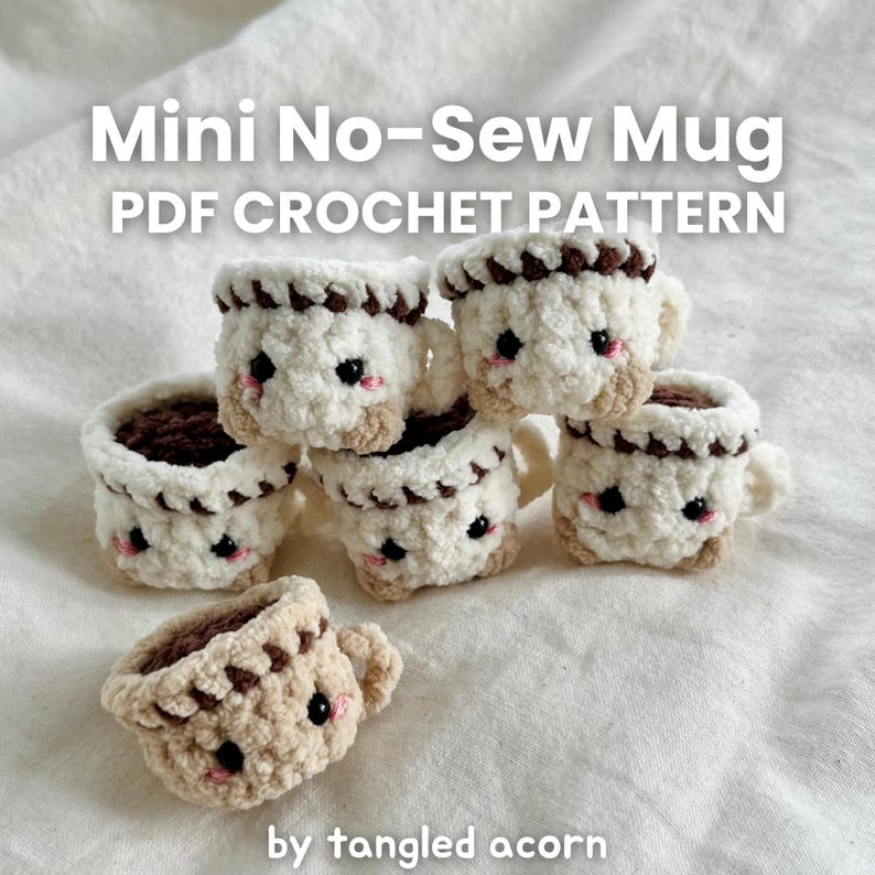 May include: A collection of six mini crochet mugs, each with a fluffy white body, brown trim, and a dark brown interior. The mugs have small handles and cute black eyes and pink cheeks. Text on the image reads "Mini No-Sew Mug PDF Crochet Pattern" and "by tangled acorn."