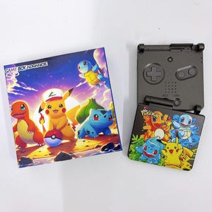 May include: A Game Boy Advance SP console with a custom Pokémon design. The console is black, with a colourful graphic on the front cover. The box also features Pokémon characters and the text "Game Boy Advance SP".