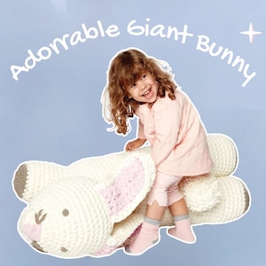 Pode incluir: Uma criança sorri sentada em um grande coelho de crochê creme. O coelho tem orelhas internas rosa e um nariz cinza. O texto "Adorable Giant Bunny" está acima da criança. O fundo é azul claro com estrelas brancas.