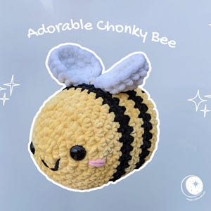 Peut inclure: Une abeille en peluche, ronde, avec des rayures jaunes et noires, des ailes blanches et un visage souriant. Le texte "Adorable Chonky Bee" est au-dessus de l'abeille. Le fond est bleu clair avec des étoiles blanches.