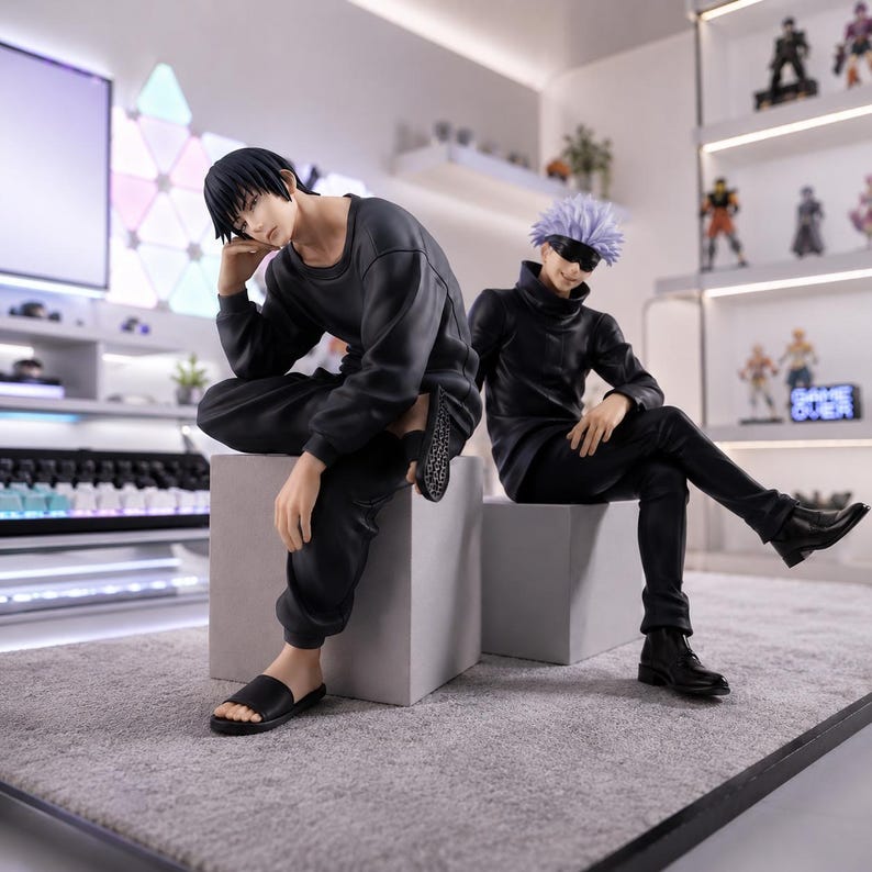 May include: Two anime-style character figures sitting on gray cubes. One figure has short black hair, wearing a long-sleeved black shirt, black pants, and black slides. The other figure has spiky light purple hair, a black blindfold, a black high-neck shirt, black pants, and black boots.
