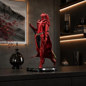 May include: A detailed collectible figurine of a warrior clad in metallic red armor with a flowing cape and a sword held at the side. The figure stands on a circular black base, featuring intricate plate armor designs and a ponytail hairstyle.