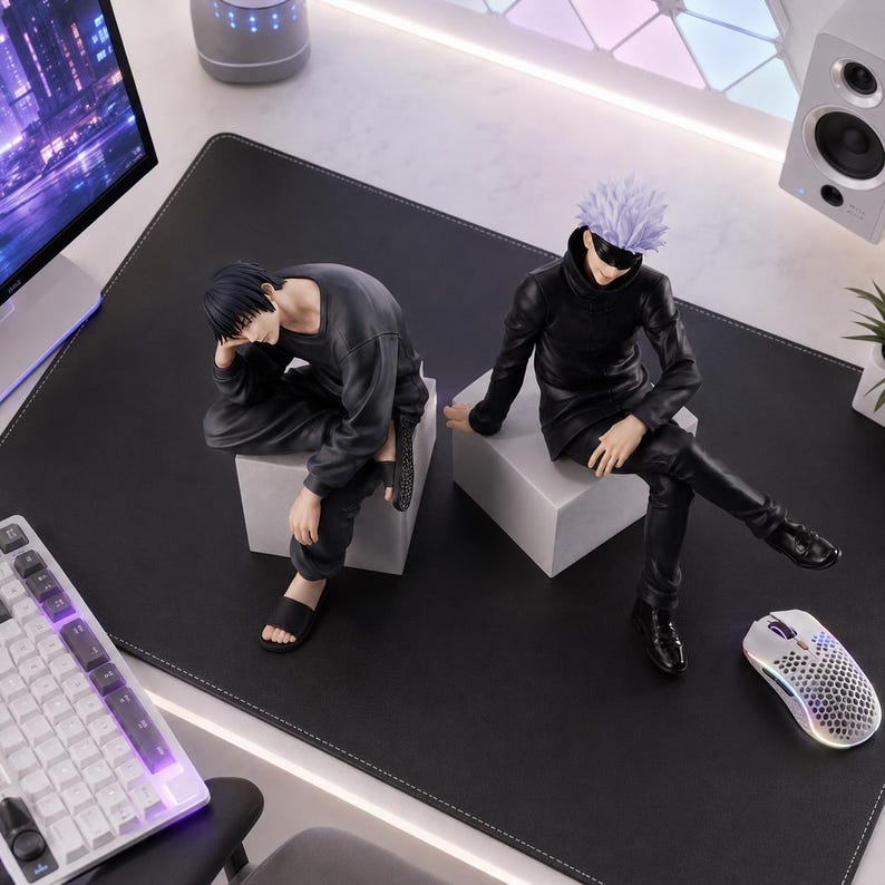 May include: Two anime-style character figures sitting on white cubes. One figure has short black hair, wearing a dark gray long-sleeve shirt, dark pants, and black slides. The other figure has spiky light purple hair, a black blindfold, a black high-neck jacket, black pants, and black shoes.