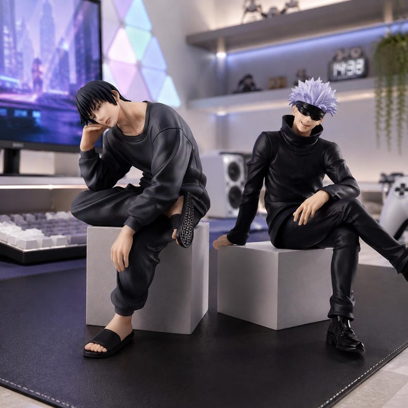 May include: Two anime character figures sitting on gray cubes. The left figure has short black hair, wearing a dark gray long-sleeve shirt, black pants, and black slides. The right figure has spiky light purple hair, a black blindfold, a black high-neck shirt, black pants, and black shoes.
