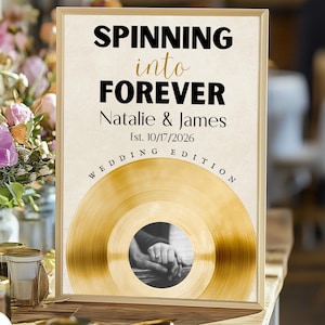 Peut inclure: Un panneau de mariage encadré avec les mots "Spinning into Forever" en noir et or. Le panneau comprend les noms Natalie & James, la date du mariage et un motif de disque vinyle doré avec une photo de mains.