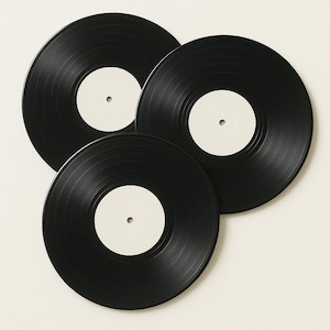May include: Three black vinyl records with blank white labels are arranged in a fan shape. The records have a glossy finish and visible grooves. The white labels are circular with a small hole in the center. The records are a classic music medium.