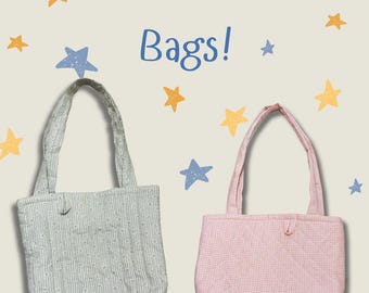 May include: Two quilted tote bags with the text Quilted Tote Bags! printed above them. One bag is light blue with a white pinstripe pattern, and the other is light pink with a small white checkered pattern. Both bags feature two handles.