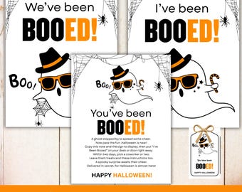 May include: Halloween-themed office decor set with three signs and a tag. The signs read "We've been BOOED!" and "I've been BOOED!" in black and orange. A ghost wearing sunglasses and a hat is featured. The tag says "You have been BOOED!"