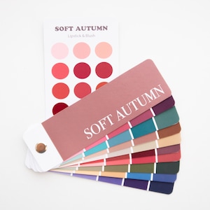 May include: A color palette fan with the text "SOFT AUTUMN" and a separate card with lipstick and blush colors. The fan displays a range of colors, including pinks, reds, blues, greens, and browns, ideal for makeup and fashion.