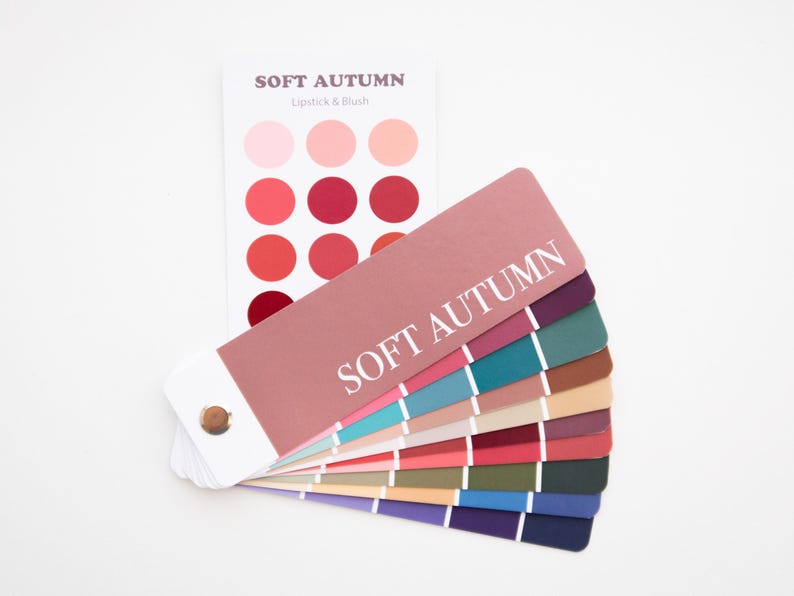 May include: A color palette fan with the text "SOFT AUTUMN" and a separate card with lipstick and blush colors. The fan displays a range of colors, including pinks, reds, blues, greens, and browns, ideal for makeup and fashion.