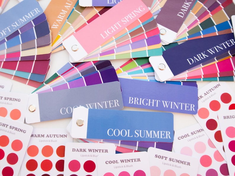 May include: A collection of color palette cards for seasonal color analysis. The cards display a range of colors, including pinks, blues, purples, and greens. Text on the cards includes "Soft Summer," "Light Spring," "Cool Winter," and "Bright Winter."