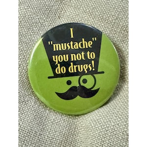 May include: A circular, green badge with the words "I 'mustache' you not to do drugs!" in yellow. The design includes a black top hat, monocle, and a mustache.