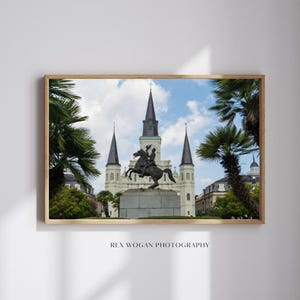 Könnte beinhalten: Gerahmtes Foto mit einer bronzenen Reiterstatue vor einem weißen Gebäude mit mehreren Türmen. Palmen umrahmen die Szene unter einem blauen Himmel mit Wolken. Der Text "REX WOGAN PHOTOGRAPHY" befindet sich unten.