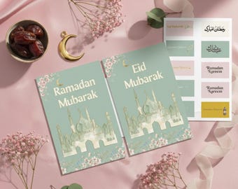 Puede incluir: Dos tarjetas de felicitación con las palabras "Ramadan Mubarak" y "Eid Mubarak" en letras doradas, con ilustraciones de mezquitas. También se ve una hoja de pegatinas con texto árabe y frases en inglés. La escena incluye dátiles, una luna creciente dorada y flores rosas.