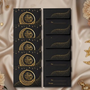 May include: Black greeting cards with gold crescent moon and star designs. The cards feature Arabic calligraphy and are arranged with matching envelopes. The envelopes have a gold glitter design and space for recipient information.