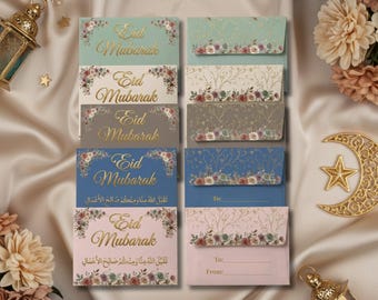 May include: A collection of Eid Mubarak greeting cards in various colors, including blue, pink, and gray, with floral accents and gold lettering. The cards are arranged on a satin surface, with decorative lanterns and a crescent moon.