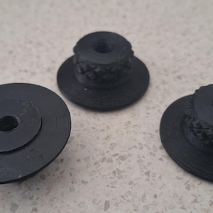 May include: Three black circular knobs with a flat base and a raised, textured cylindrical centre featuring a diamond-patterned grip. Each knob has a central threaded hole, showing a consistent design and matte finish across all three pieces.