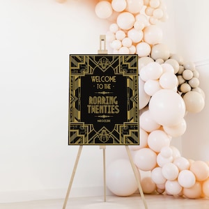 May include: A black and gold art deco style sign on a wooden easel. The sign reads "Welcome to the Roaring Twenties" with the date March 25, 20xx. A balloon arch in shades of white and peach is in the background.