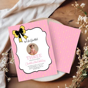 May include: Pink birthday invitation with a photo of a young girl. The invitation features a yellow bow, the text "Isn't she Beautiful", and details for a third birthday celebration. The background is pink with yellow bows.