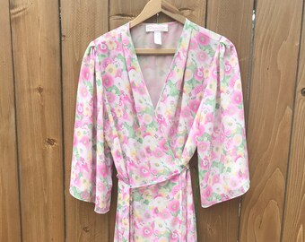 May include: A pink and green floral print wrap dress with a long sleeve and a tie at the waist.
