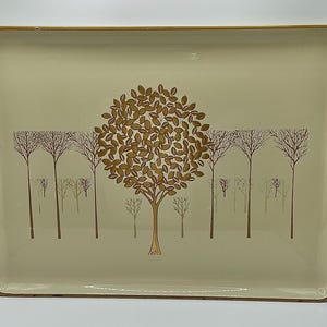 May include: Rectangular serving tray with a cream-colored background and a brown tree design. The tray has a gold-colored border and features a large tree with leaves and several smaller trees in the background.