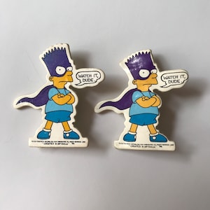 May include: Two white cardboard stickers featuring a cartoon character with yellow skin, blue hair, and a purple cape. The character is wearing a blue shirt and blue pants. The character is holding their arms crossed and has a stern expression. The text "Watch it, dude." is written in a speech bubble above the character's head.