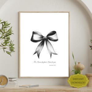 以下が含まれることがあります： フレームに入った白黒プリントで、リボンの詳細なイラストが描かれています。リボンは細かい線で影付けされており、奥行きを感じさせます。リボンの下には「For I know the plans I have for you Jeremiah 29:11」と書かれています。