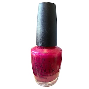 May include: A bottle of OPI Nail Lacquer in a vibrant pink shade with a shimmering finish. The bottle has a black cap and the brand name is visible on the front. The bottle contains 0.5 fl oz of nail polish.